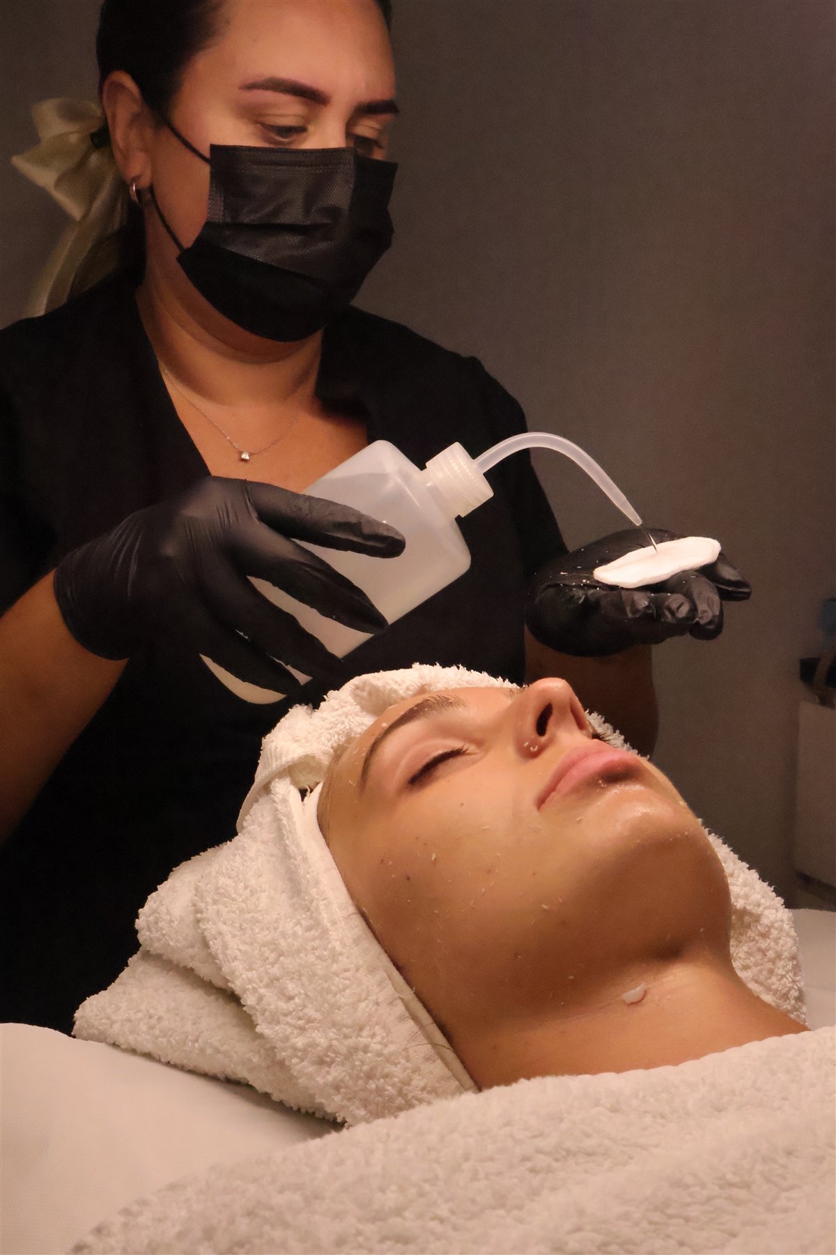 Therapist preparing a cotton pad to cleanse the skin during a facial at BeCammo, Malta